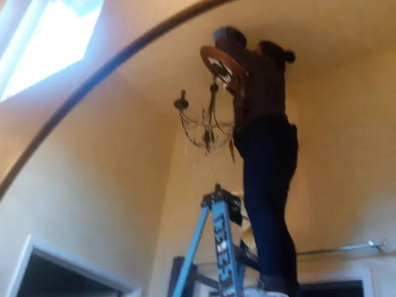 Electrician installing a chandelier in a Lehigh residence